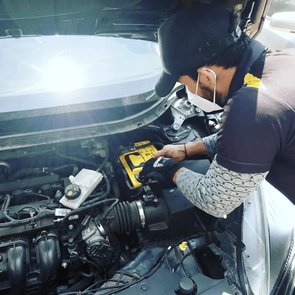 instalacion-bateria-domicilio-tecnico-guayaquil Técnico especializado instalando una batería a domicilio en el motor de un vehículo en Guayaquil.